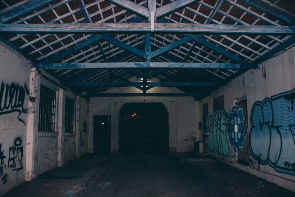 Creepy dark abandoned warehouse interior featuring colorful graffiti art.