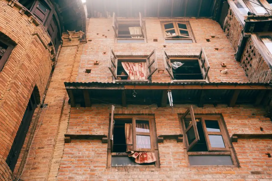 Sunlit view of an old brick building facade with wooden windows and ornate architecture.